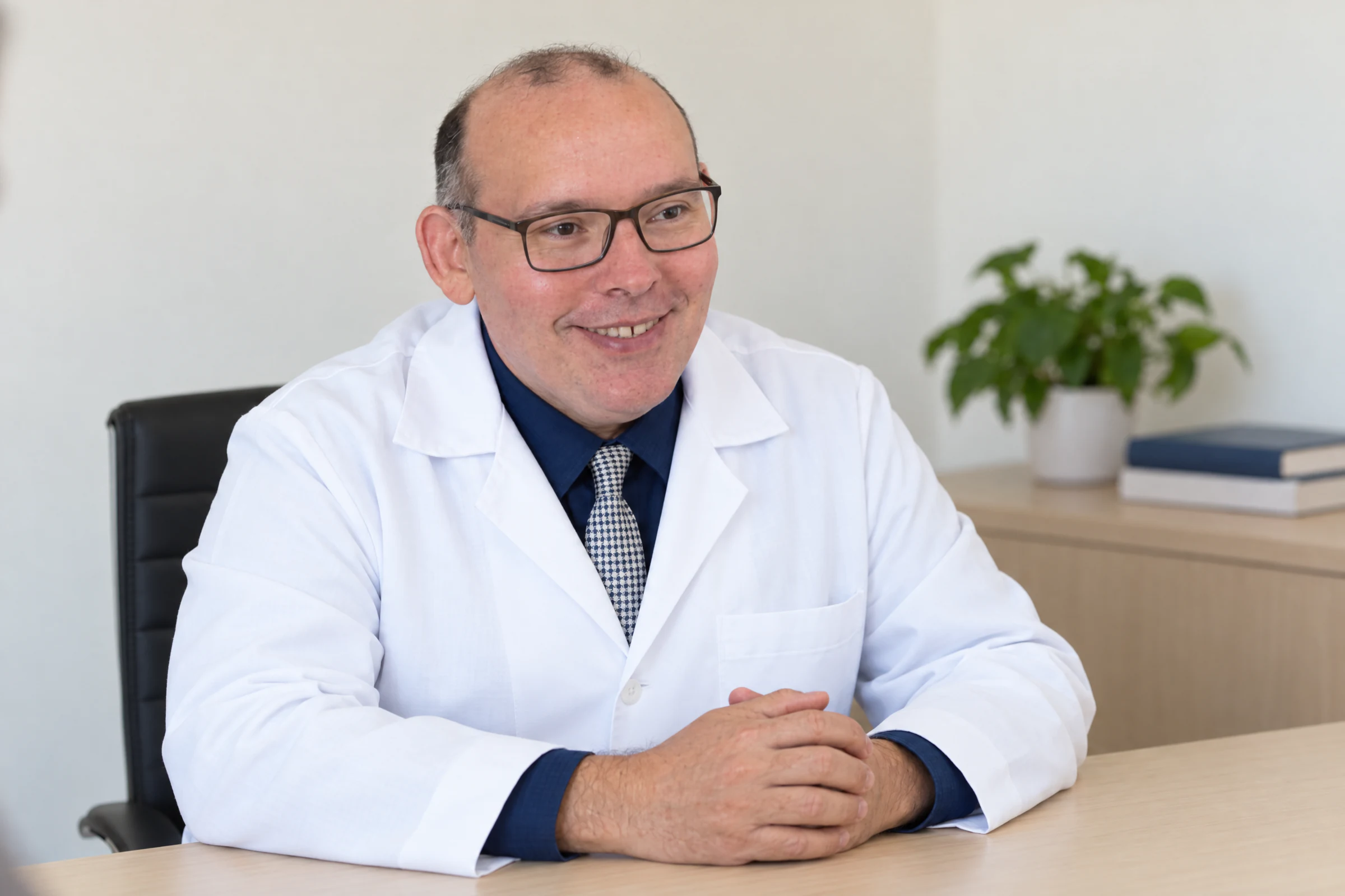 Dr. Avelino Júnior sentado à mesa, ouvindo com atenção durante a consulta